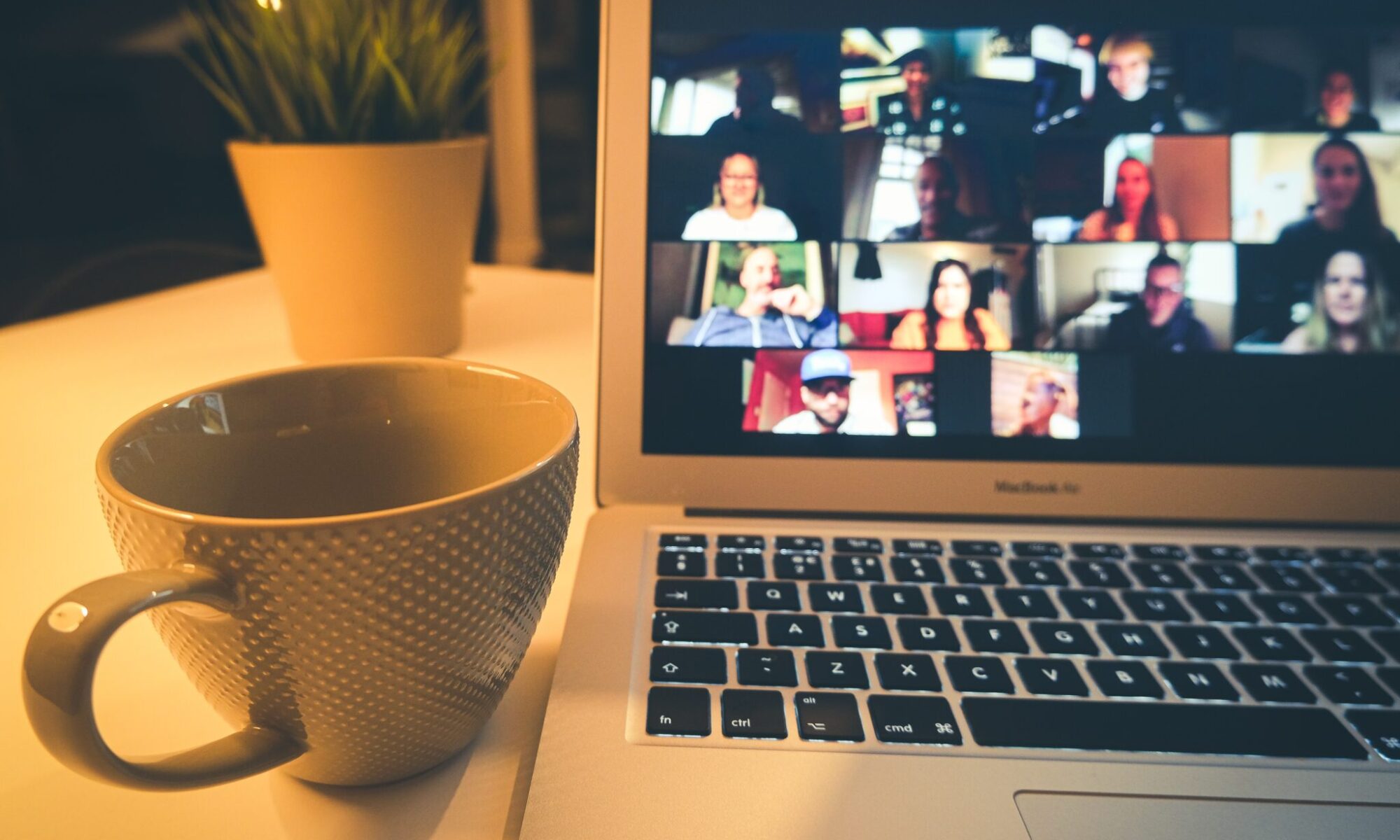 A zoom screen on a laptop with a coffee cup next to it